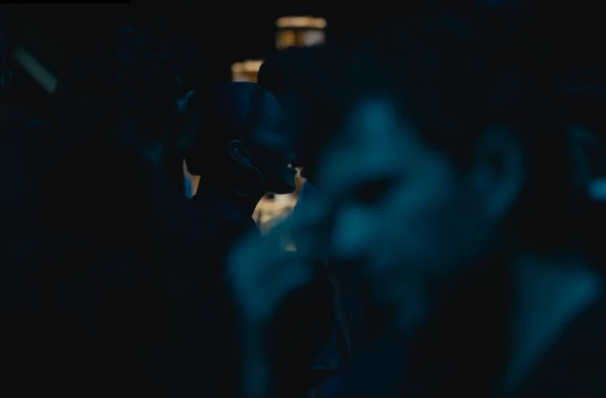 Figures at an evening gathering in blue light.